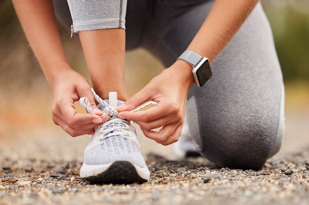 Shoes, fitness and exercise with a sports woman tying her laces before training, running or a workout. Hands, health and cardio with a female runner or athlete getting ready for an endurance run
