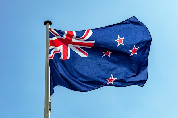 New Zealand flag, New Zealand national symbol waving against clear blue sky, sunny day