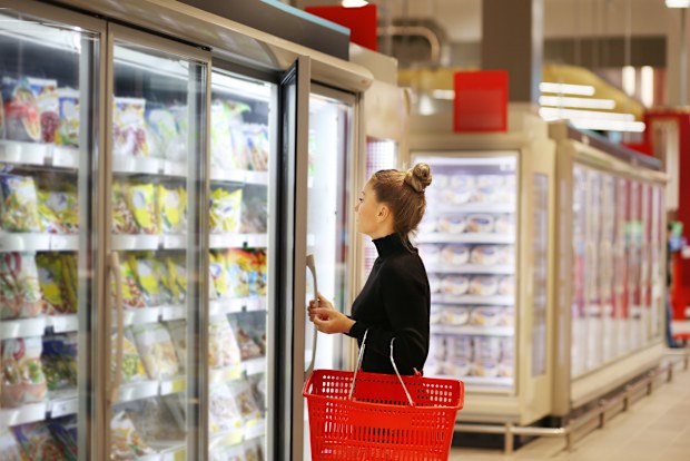 Woman choosing frozen food from a supermarket freezer stock