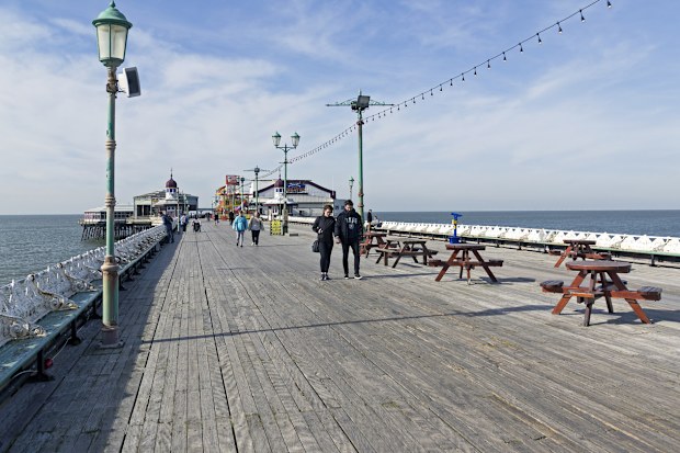 View of a train on Blackpool's pier, UK.  People can be seen on the promenade