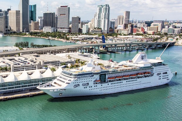 Miami, United States - March 9, 2017:  A large Royal Caribbean cruise-line ship docked at the terminal with downtown Miami, Florida rising in the background.