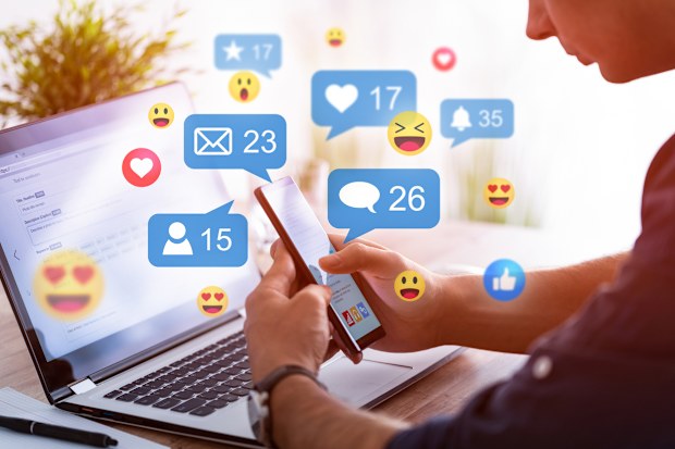 Man looking at screen with emojis.