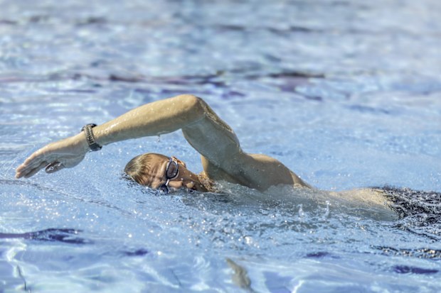 A male swimmer swims crawl in a swimming pool during training for a triathlon.