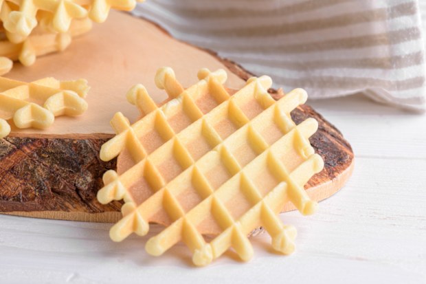 Ferratelle or pizzelle a traditional dessert or cookies on a cutting board with napkin on white wooden background, close up. Regional cuisine of Abruzzo, Italy. Like the well-known waffle