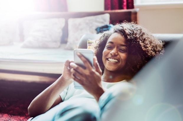 Young woman using phone, smiling. Woman on the phone. Woman texting. Woman making a phone call.