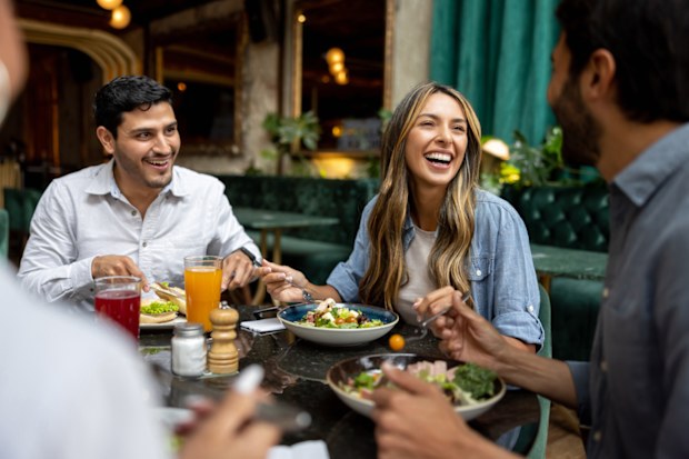 Happy group of friends having lunch together at a restaurant and laughing