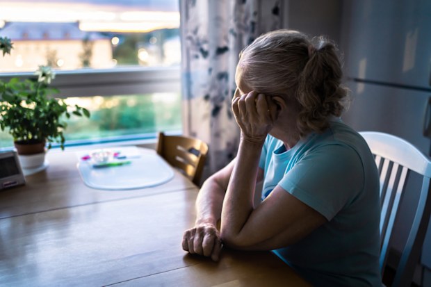 An elderly woman looking out the window at home