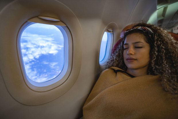 Portrait of a beautiful woman traveling by plane and sleeping during the flight - travel concepts