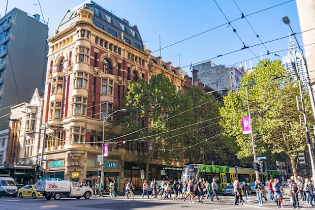 Melbourne, Australia - April 03, 2017: Melbourne city life. People crossing Collins street with traffic of cars and tram