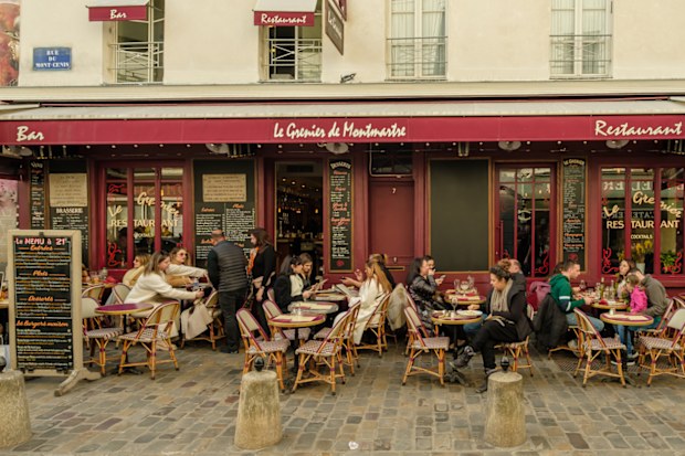 Paris, France - February 17, 2024 : View of people sitting outdoors and enjoying dinner and drinks at a restaurant bistro in Montmartre Paris France