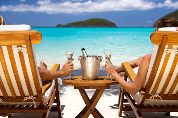 Couple drinking champagne in sun chairs on a beach | Honeymoon holiday couple
