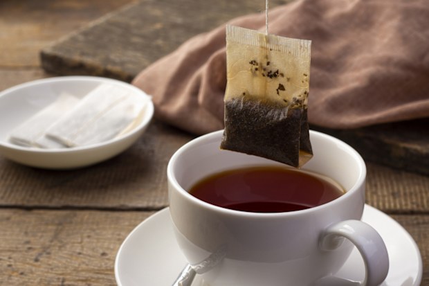 Close up Tea bag, Black tea in white cup on wooden table