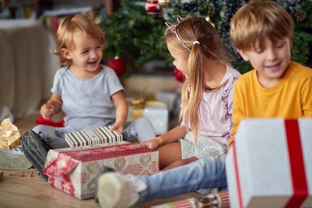 Cute little kids  opening  Christmas gift at home.