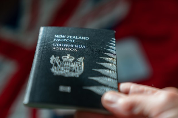 New Zealand passport in selective focus effect held  with background flag of country