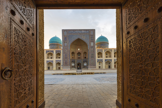 Blue domes of the Madressa through open wooden door in Bukhara, Uzbekistan.