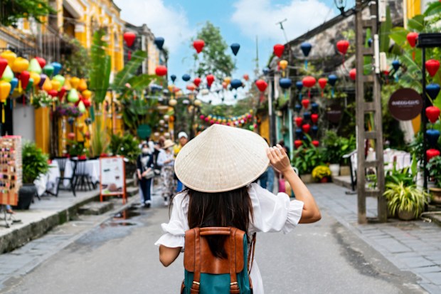 Carefree tourist woman wearing Non La (traditional Vietnamese hat) enjoy sightseeing in Hoi An old town Vietnam. Copy space, closeup