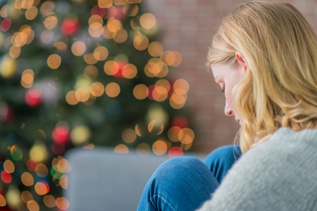 Woman sad at Christmas. Woman and Christmas tree. Sad woman.