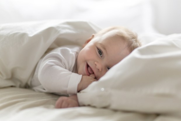 A happy baby laying in bed