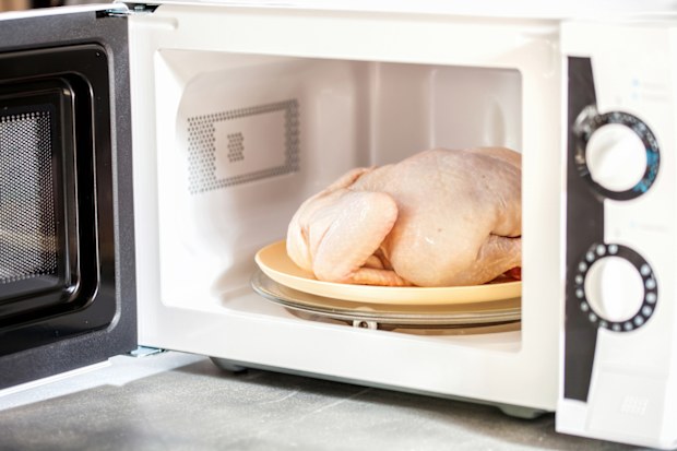 The defrozen raw chicken in the microwave. Selective focus.