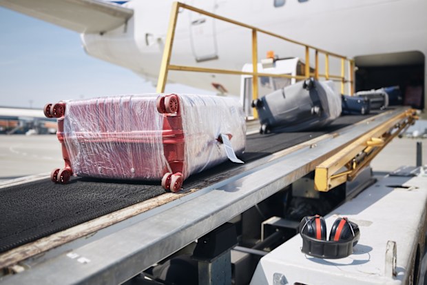Loading of luggage to airplane. Suitcases on conveyor belt to plane.