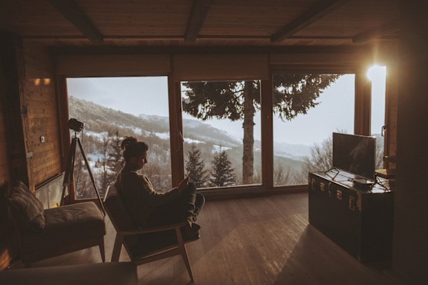 Photo of a young woman enjoying moments alone and reading news online, during her winter vacation in the mountains