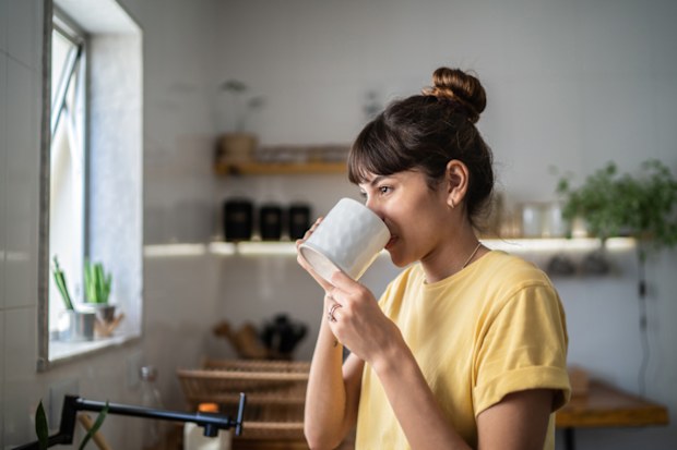 Young woman drinking coffee or tea at home
