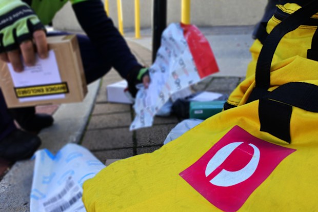 Perth, Wa - May 11 2021:Australia Post courier loading postal packages into a bag.Australia Post is the government business enterprise that provides postal services in Australia.
