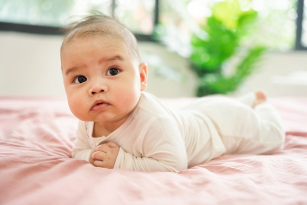 newborn baby laying on pink bed sheet