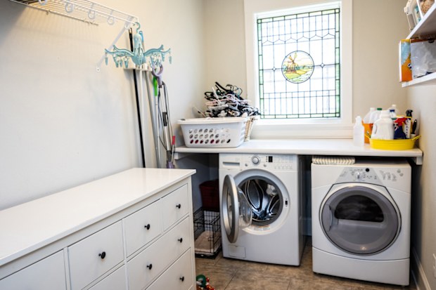 a laundry room with a top loader washing machine, dryer, counter and dresser