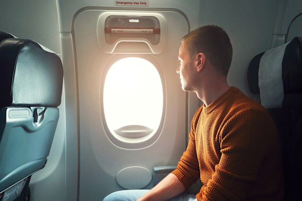 Comfortable traveling by airplane. Curious young passenger looking from the window. - selective focus