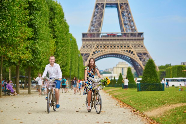 Romantic couple riding bicycles near the Eiffel tower in Paris