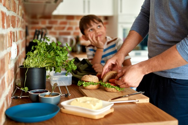 Father making lunch for son in kitchen. Dad making school lunches. Sandwich. 