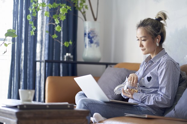 woman working from home using laptop computer eating snacks