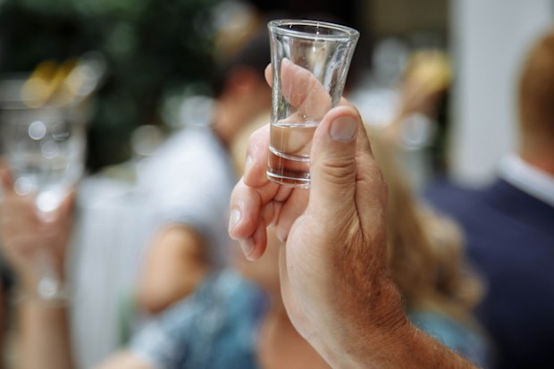 Man's hand holding a glass with vodka