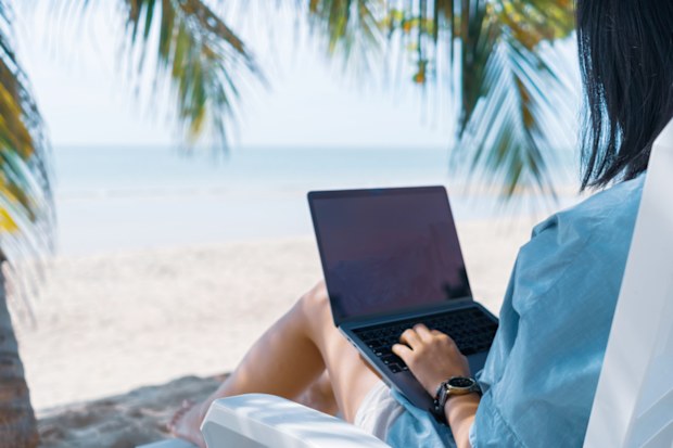 Woman using laptop and smartphone to work study in vacation cady at beach background. Business, financial, trade stock market and social network concept. istock