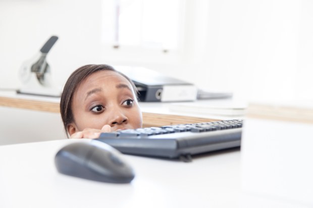 Woman afraid of boss. Woman ducking under office desk.