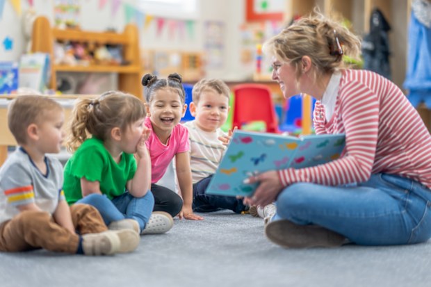 Daycare teacher sitting on the floor with preschool age children