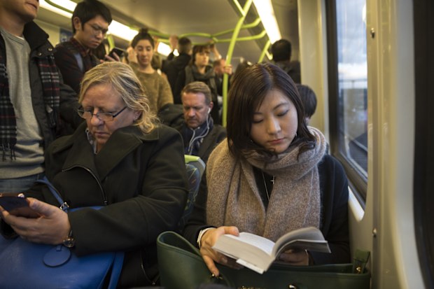 At the end of a work day, commuters ride a metro train traveling from Flinders Street Station to points outside the city center of Melbourne, Australia