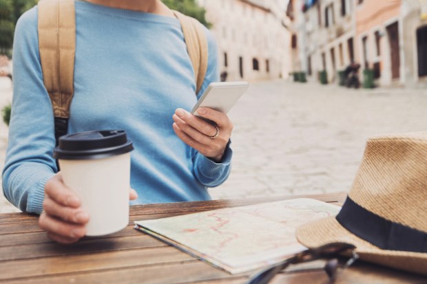 Young woman using phone in a cafe, travel concept