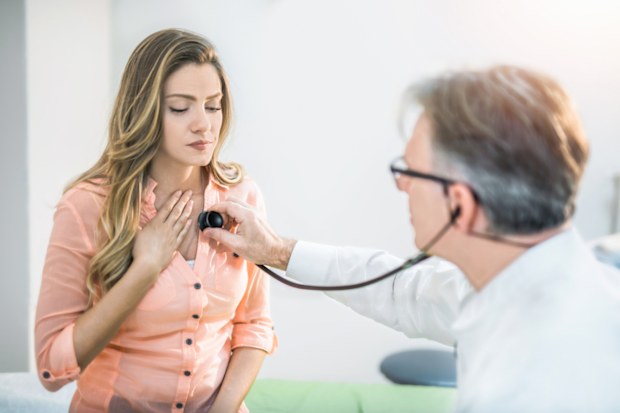 Young woman getting her chest examined by a doctor.