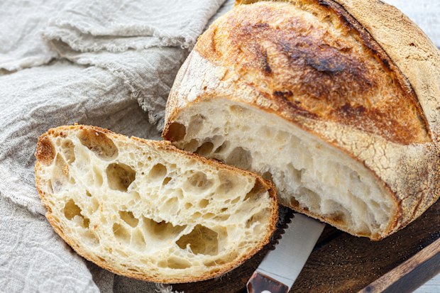 Cut loaf of french artisanal bread on a linen cloth, selective focus.