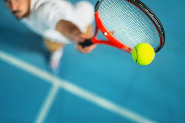 Man playing tennis on a blue court