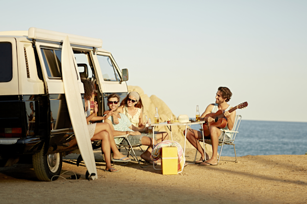 Van life: people gathered around a camper at the beach