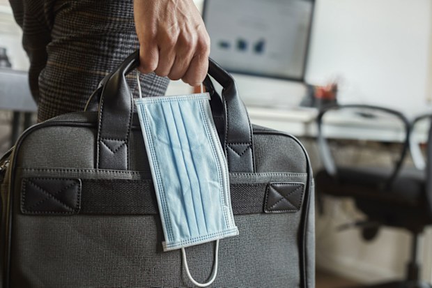 Office worker carrying laptop and coronavirus mask