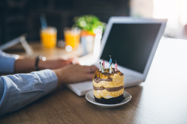 Office birthday cake while typing on a laptop computer at desk