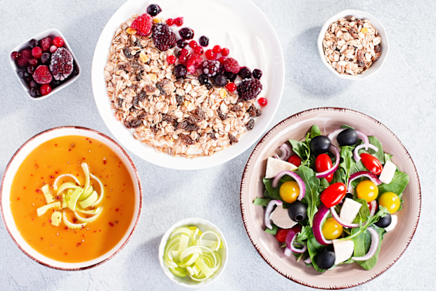 Unprocessed healthy foods, including soup, oats, berries, fresh salad