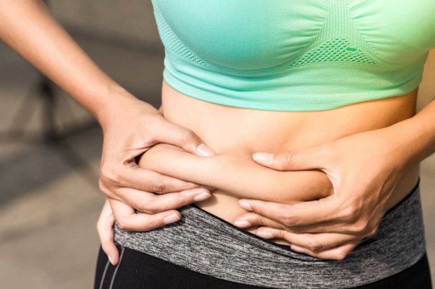 Woman in active wear pinching stomach