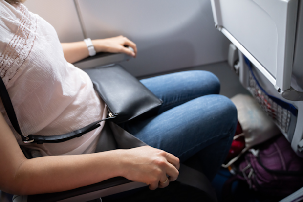Woman in plane window seat using both armrests