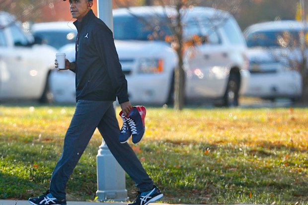 President Barack Obama carries a pair of sneakers as he arrives for a private game of basketball at Fort McNair in Washington. (AAP)