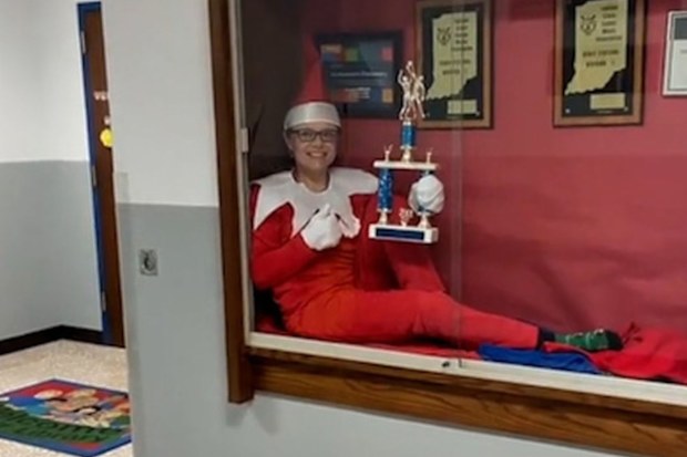 Beth Hoeing sitting in the school's trophy cabinet dressed as an elf.